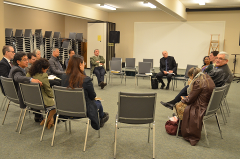 Adults sitting on chairs in a circle, studying the Bible