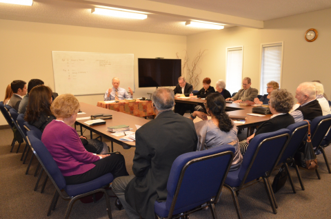 Adults sitting around tables, studying the Bible